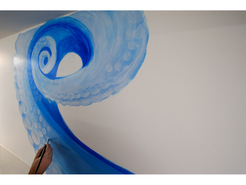 barber using styling spray on young man with black hair, short on sides and long in a quiff on top